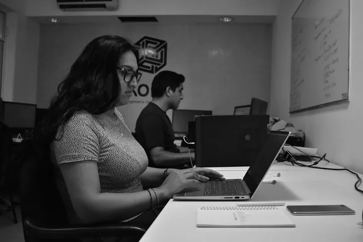 Persona de Kore trabajando con una laptop y pantalla de código.